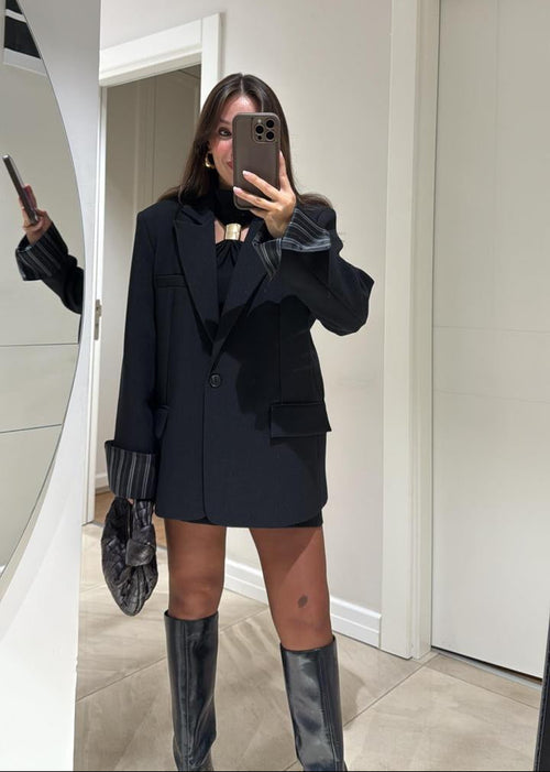 Ce blazer oversize pour femme, d’une élégante teinte bleu marine, est une pièce moderne et polyvalente, parfaite pour un look décontracté chic ou plus habillé. Sa coupe ample et légèrement structurée offre un confort optimal et une silhouette contemporaine.
Il présente un col à revers classique et une fermeture à un seul bouton foncé.

La particularité de ce blazer réside dans sa doublure rayée (blanc et marron/rose pâle), qui devient visible lorsque les manches sont retroussées ou lorsque le blazer est lég